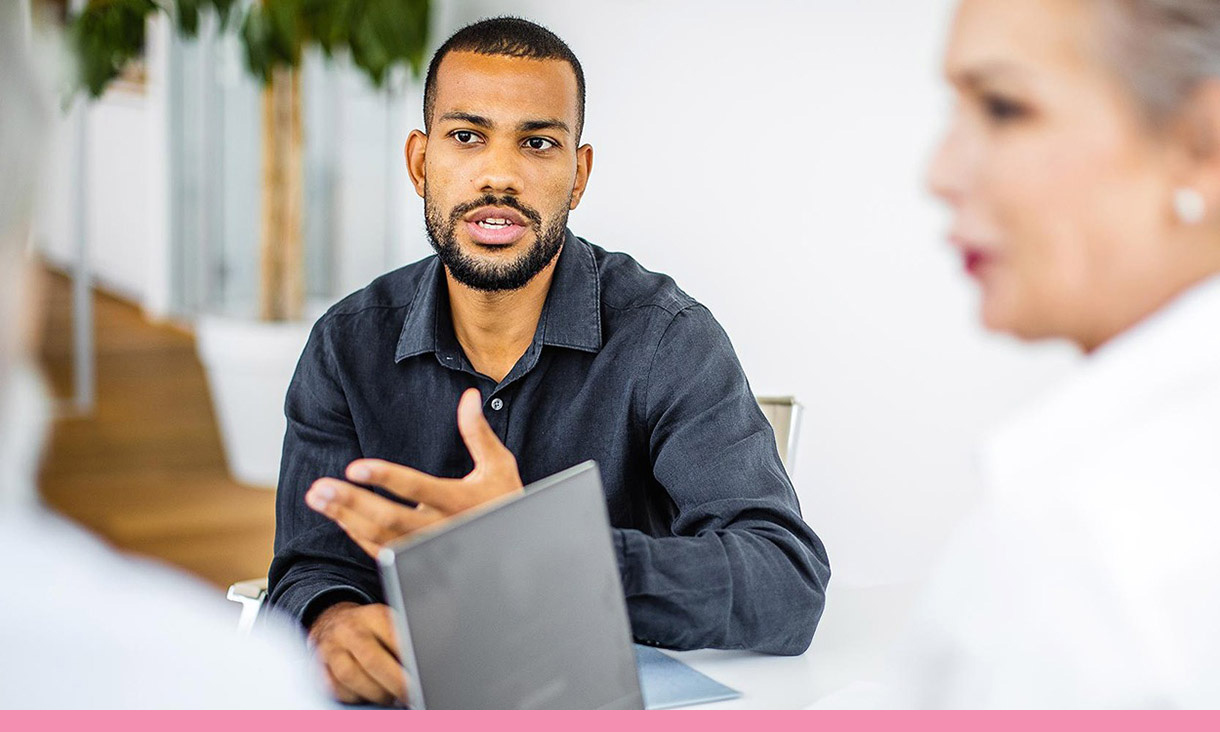 A man talks in a meeting with others.