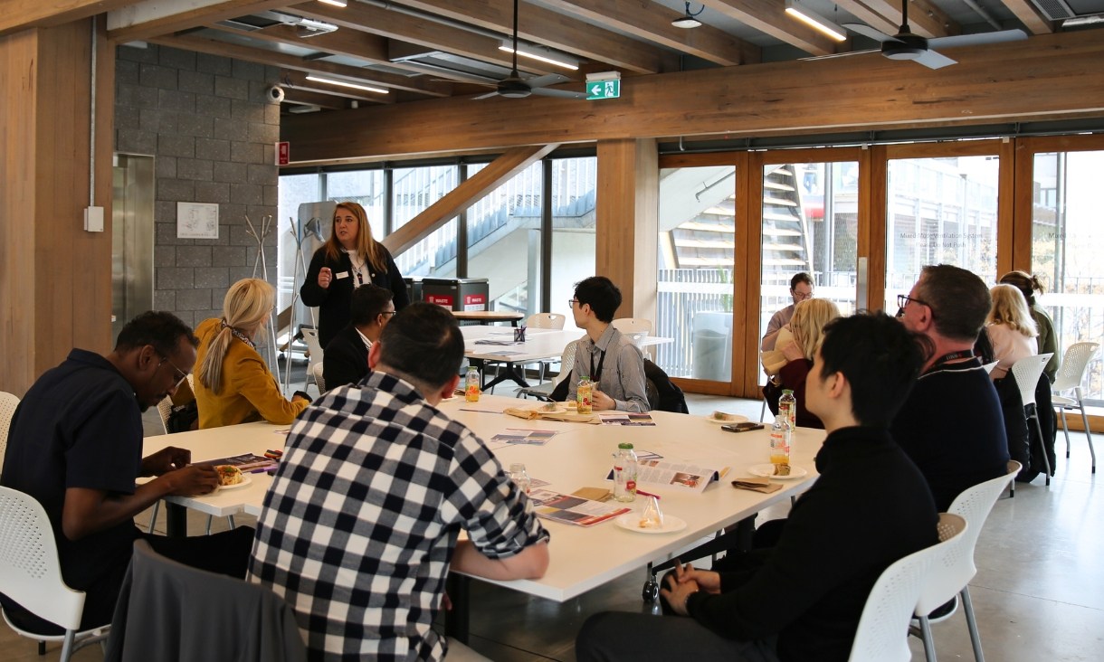 People sitting around table listening to speaker