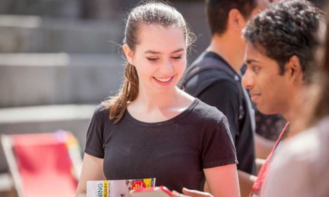 A female student helps another at an event.
