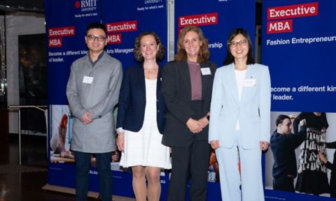 Four people in front of Executive MBA banner