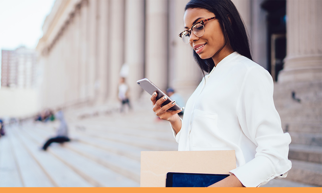 A lawyer looks at her phone outside a courthouse.