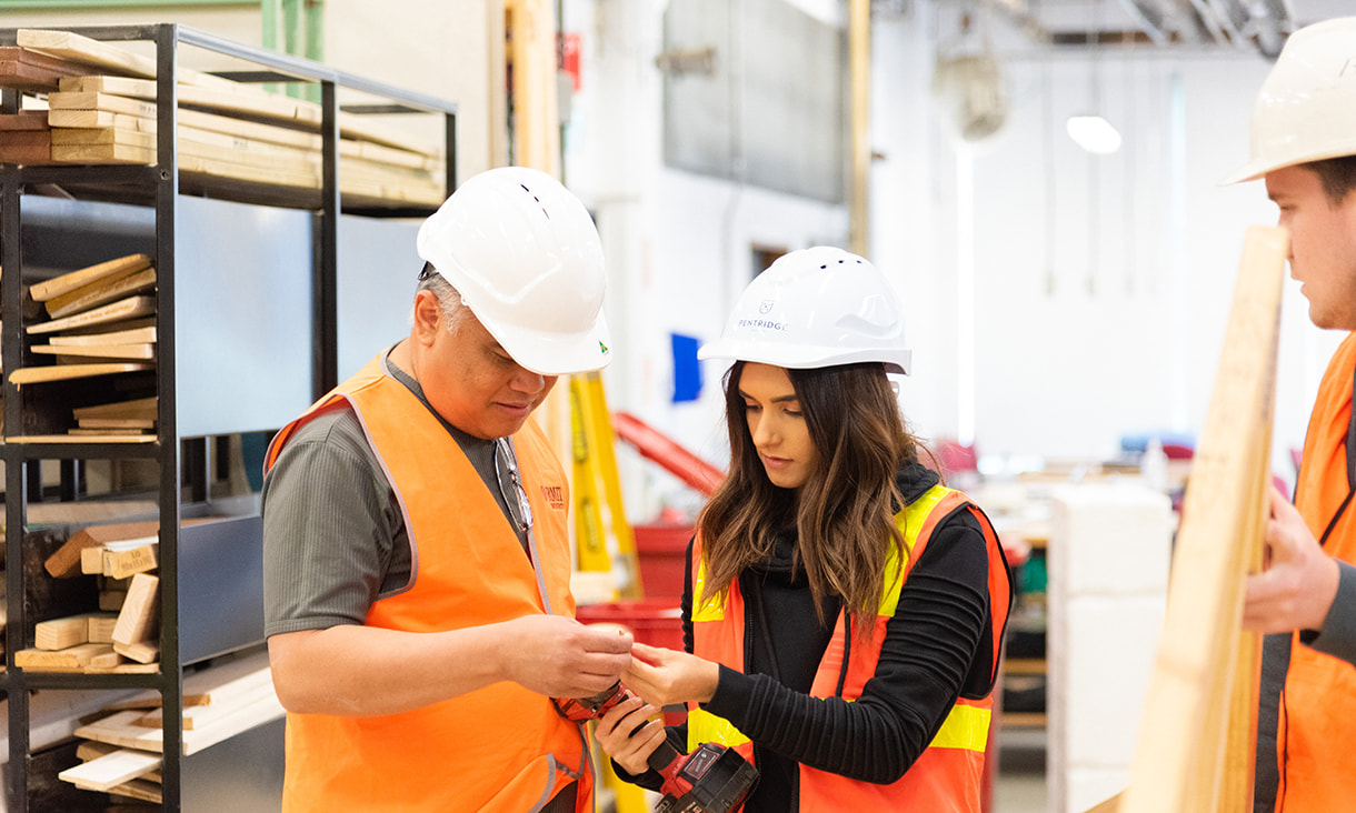 Student and teacher wearing personal protective gear while holding a power tool