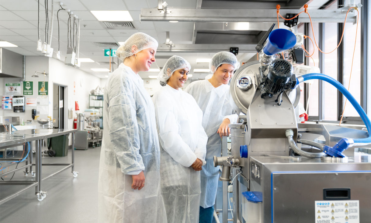 Three student's stand together in a high-tech food-technology lab at RMIT's Bundoora campus