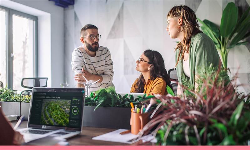 A men and two women work collaboratively at a desk.