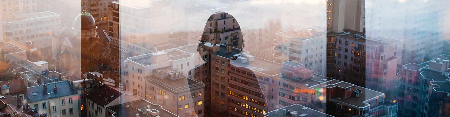 Reflection of a lady from the top floor of a skyscraper overlooking a city.