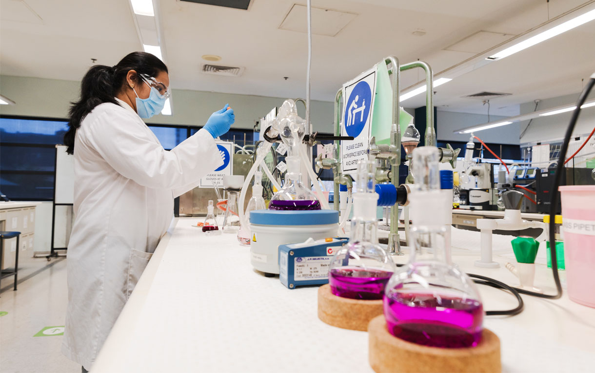 A student working with chemicals in a laboratory filled with chemistry equipment