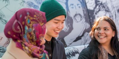 A group of three RMIT students, all laughing and looking at each other