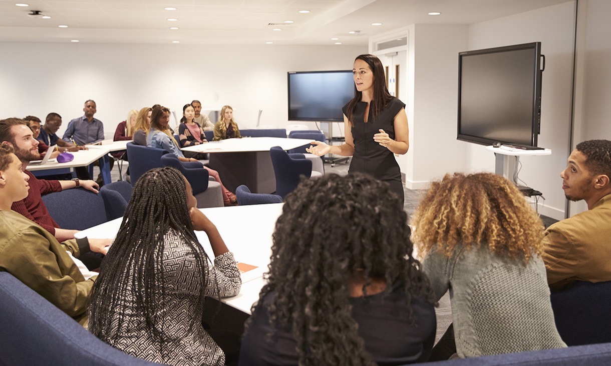 Female teacher addressing university students in a classroom